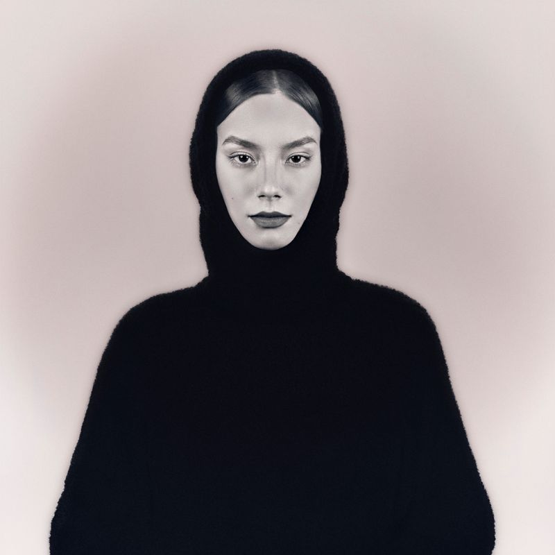 Elegant black and white portrait of a woman in a hooded sweater, exuding grace and style.
